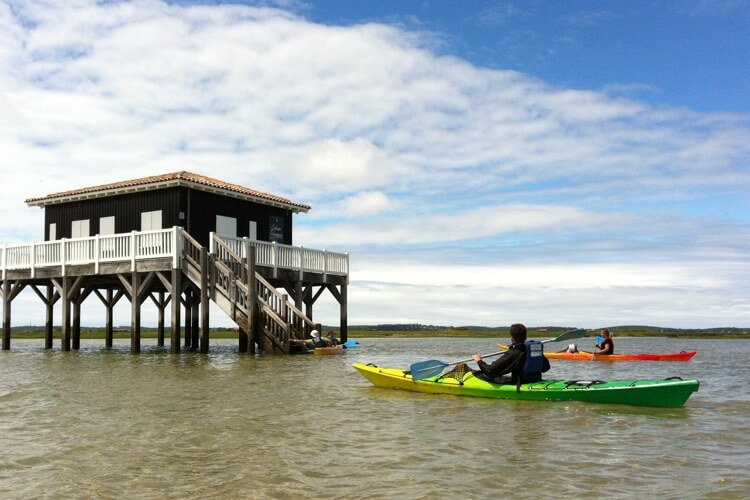 3 kayaks de mer devant des cabanes tchanquées du bassin d'Arcachon